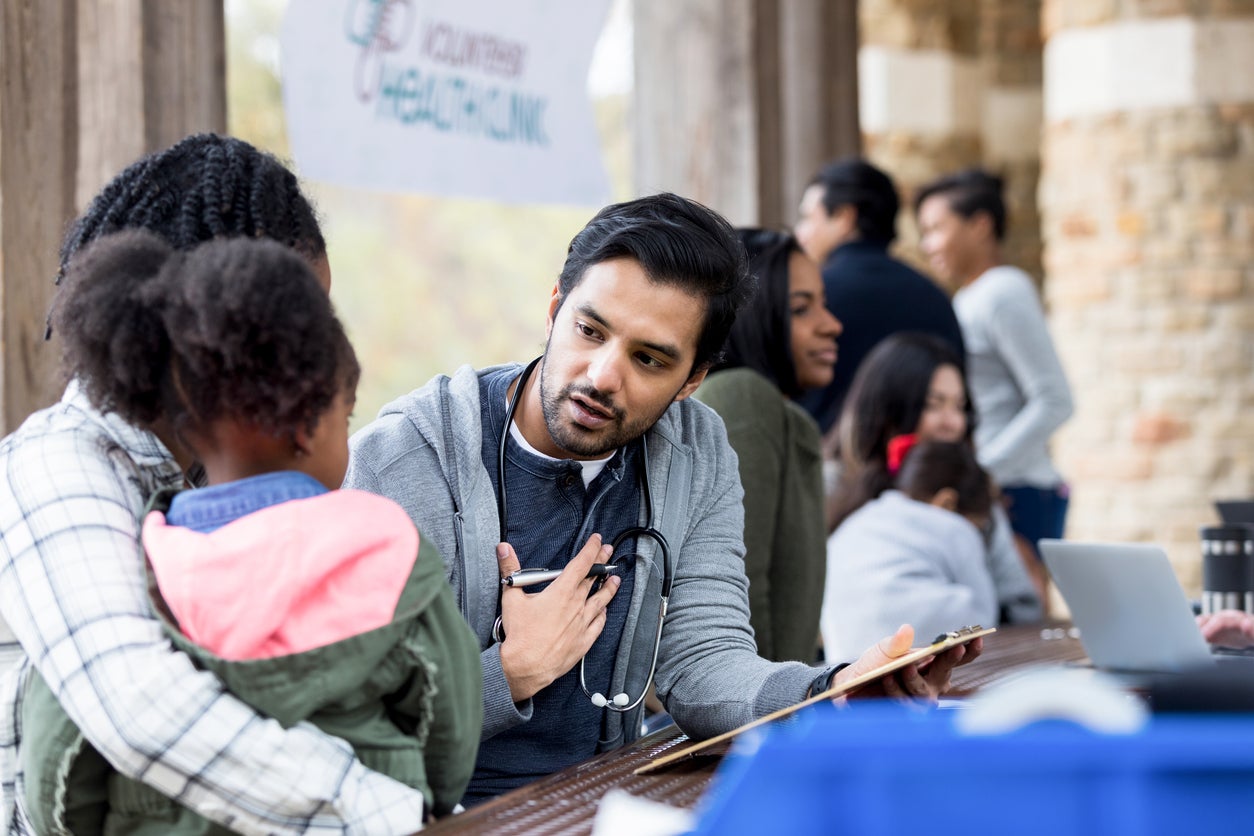 Healthcare provider speaks with a parent and young child during a community health event.